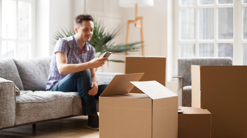Man relaxed on sofa with boxes in room